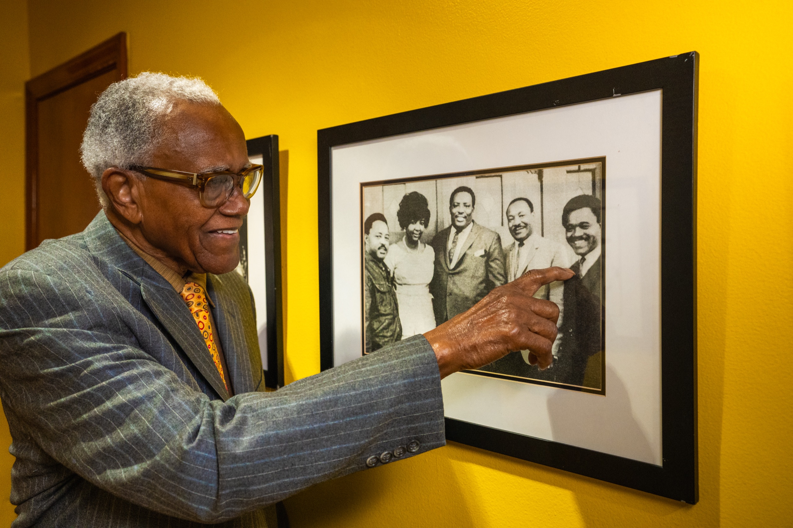 JT Johnson pointing to framed family history photos during a documentary interview
